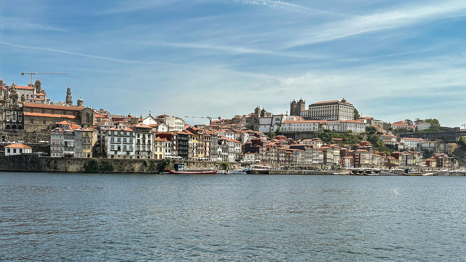 The colourful houses of the Ribeira waterfront in Porto rising above the Douro river, with the cathedral on the hill above